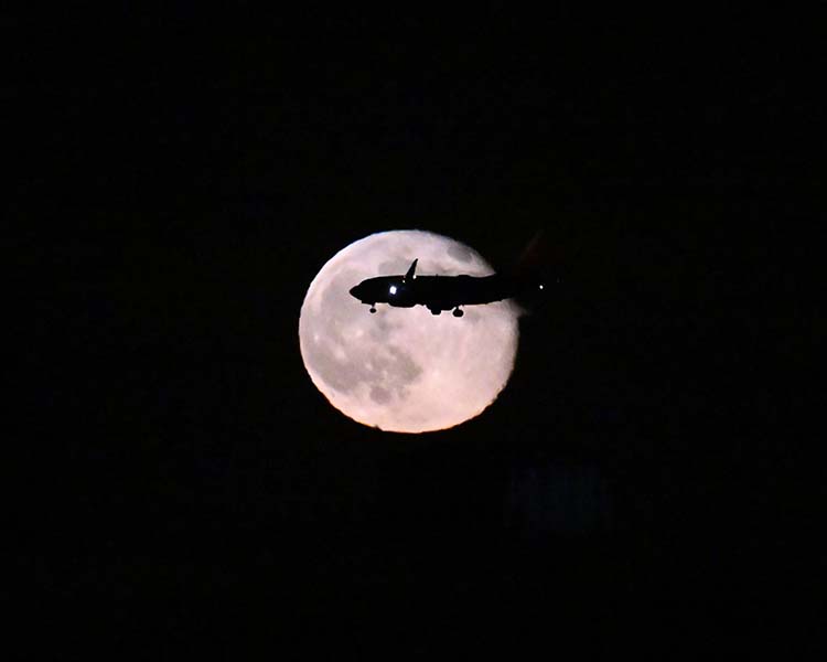 Airplane silhouette crossing the full moon